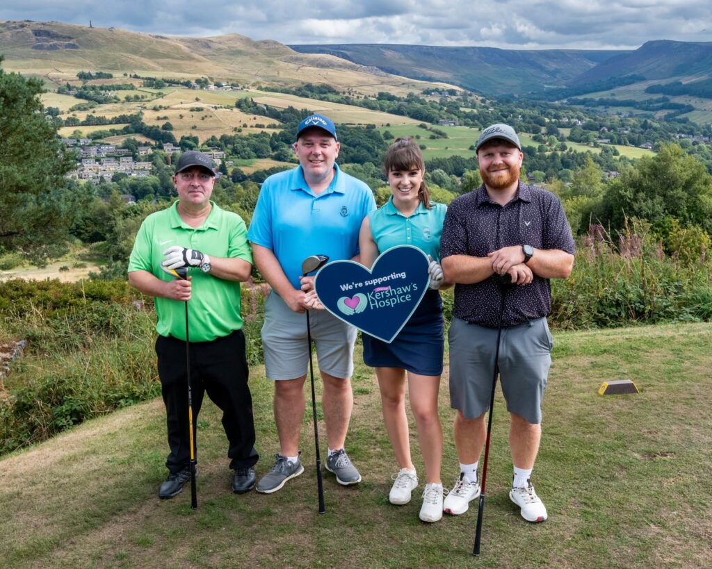 A group of three men and one women standing on a hill in front of the pennines