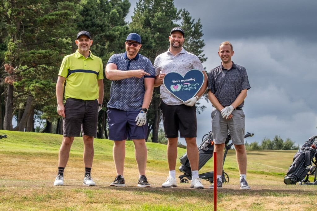 A group of men standing with their golf clubs on the golf course