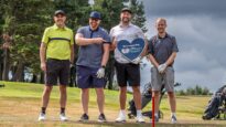 A group of men standing with their golf clubs on the golf course