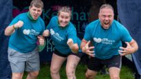 Two men and one women posing in Dr Kershaw's Hospice t-shirts, covered in mud