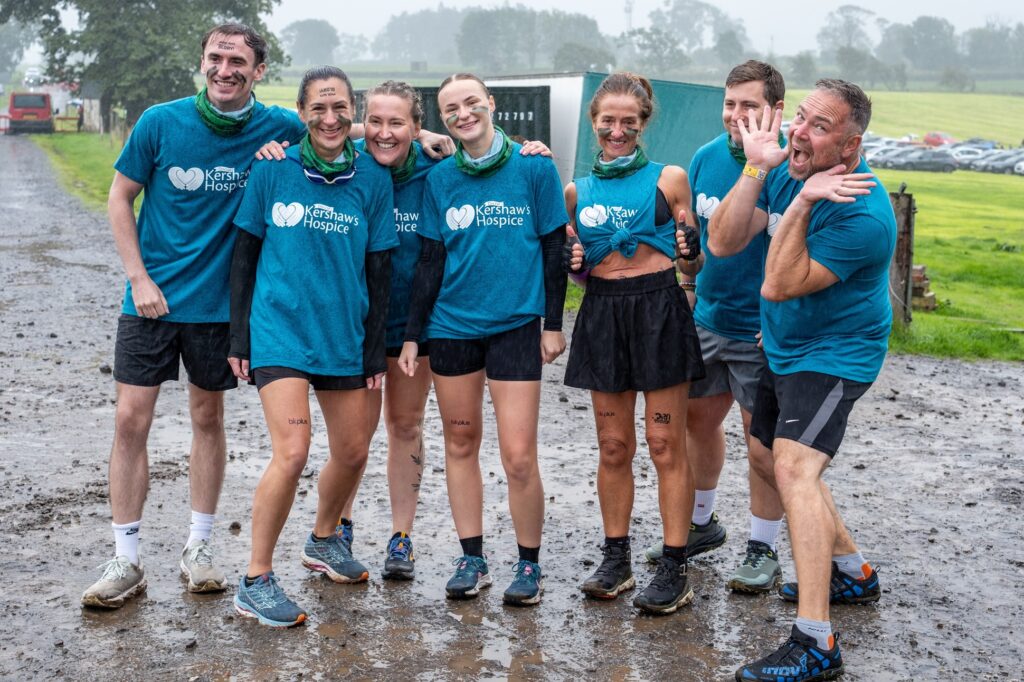 A group of people in Dr Kershaw's Hospice t-shirts standing together in the mud