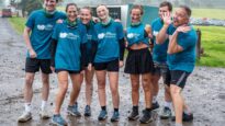 A group of people in Dr Kershaw's Hospice t-shirts standing together in the mud