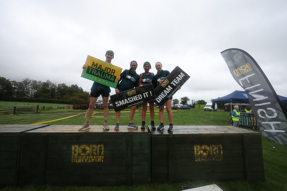 A group of four people standing on top of Born Survivor blocks holding signs saying 'Major Trauma', 'Smashed It' and 'Dream Team'