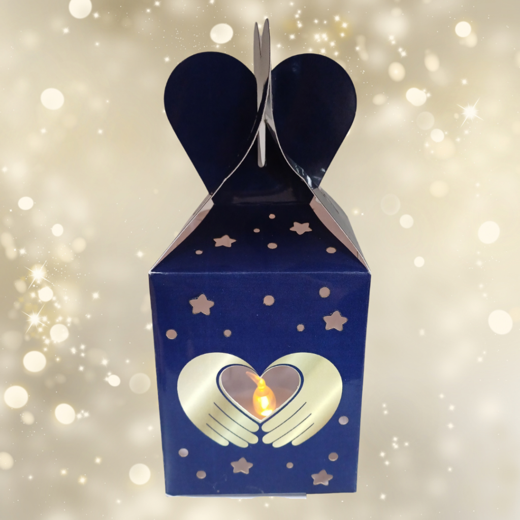 Rectangular paper lantern in dark blue with gold stars and two gold hands in the shape of a heart. Inside is a tea light.