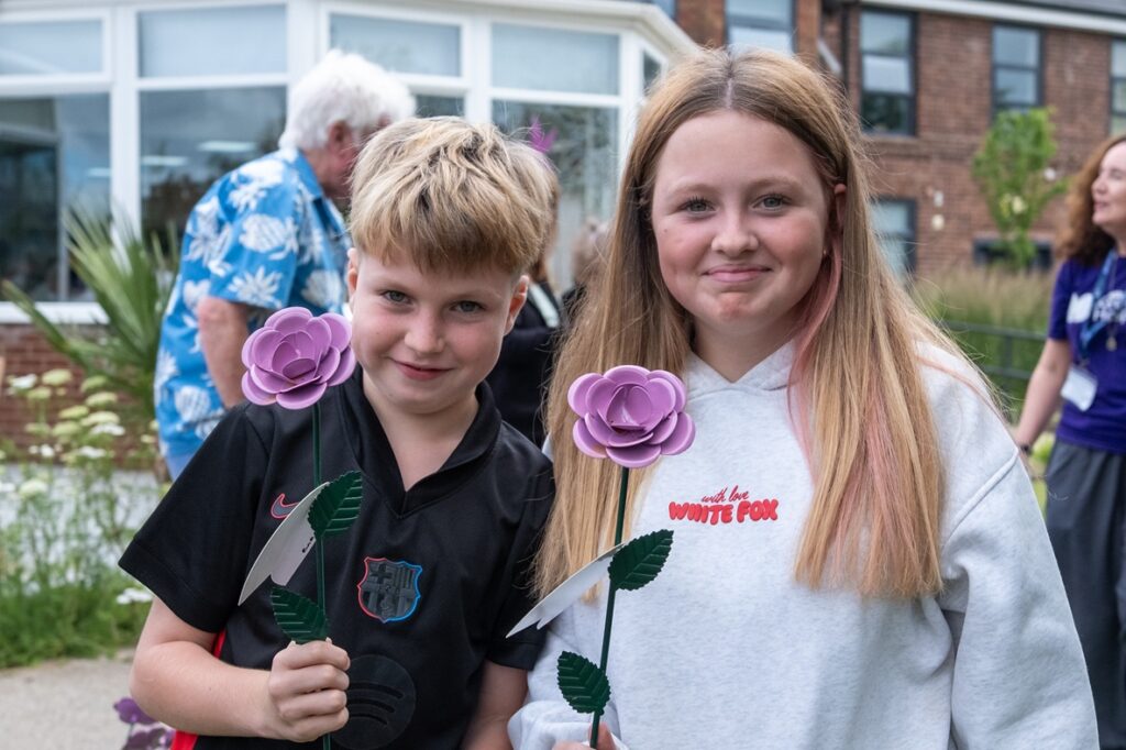 A young boy and girl holding their lilac Rose to Remember roses