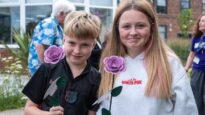 A young boy and girl holding their lilac Rose to Remember roses