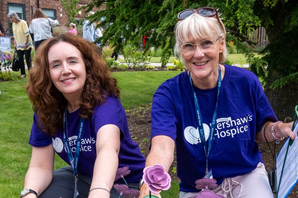 Two Dr Kershaw's Hospice volunteers planting lilac roses in the gardens