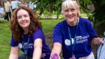 Two Dr Kershaw's Hospice volunteers planting lilac roses in the gardens