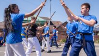 Children dressed in blue holding up sticks