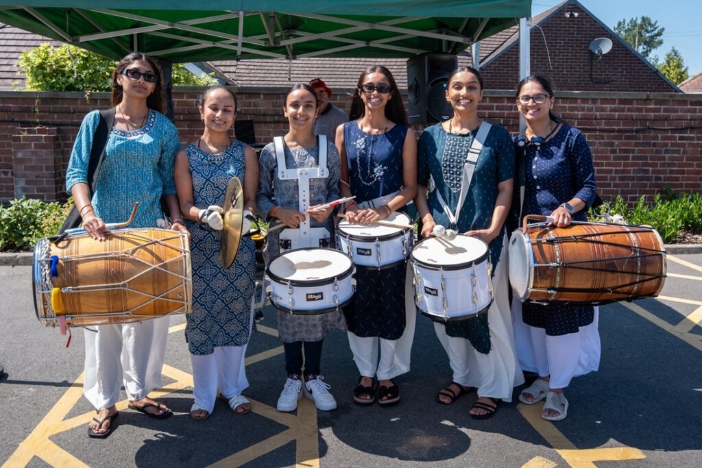 A group of smartly dressed Asian women holding drums
