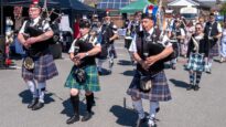 A crowd of men in kilts playing the bagpipes as they walk towards Dr Kershaw's Hospice