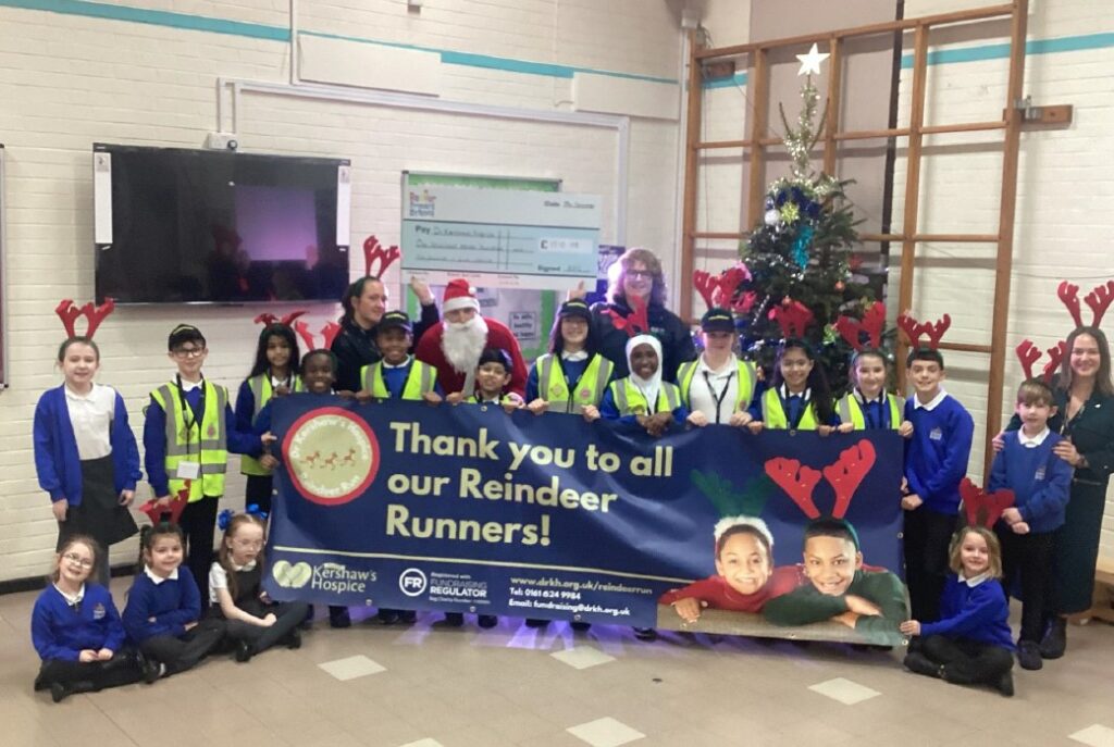 Children in a school hall with a large sign saying 'Thank you to all our Reindeer Runners'
