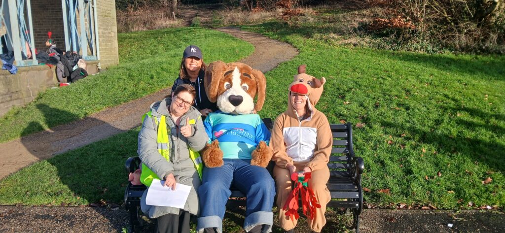 Hartley the dog mascot sitting on a bench with teachers