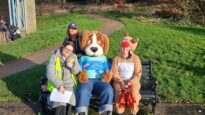 Hartley the dog mascot sitting on a bench with teachers