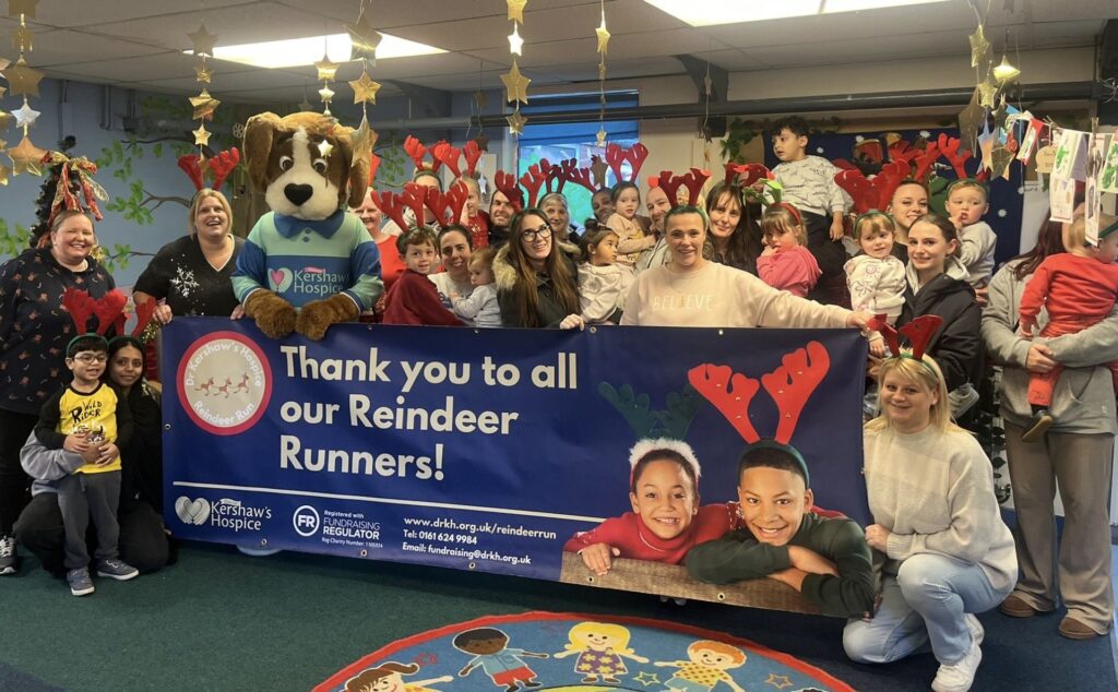 Children, teachers and Hartley the dog mascot holding a sign saying 'Thank you to all our Reindeer Runners'