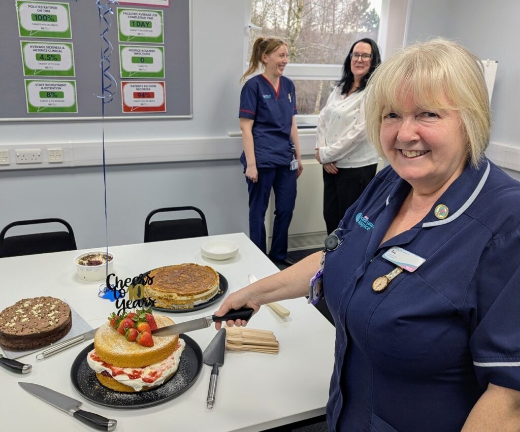 Female nurse smiling and cutting a cake