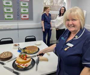 Female nurse smiling and cutting a cake