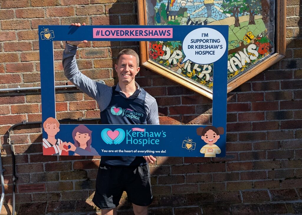 Man holding up an 'I'm supporting Dr Kershaw's Hospice' sign