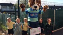Hartley the mascot with school children and a cheque for £1,287