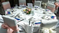 A beautifully decorated white table with chairs adorned in bows
